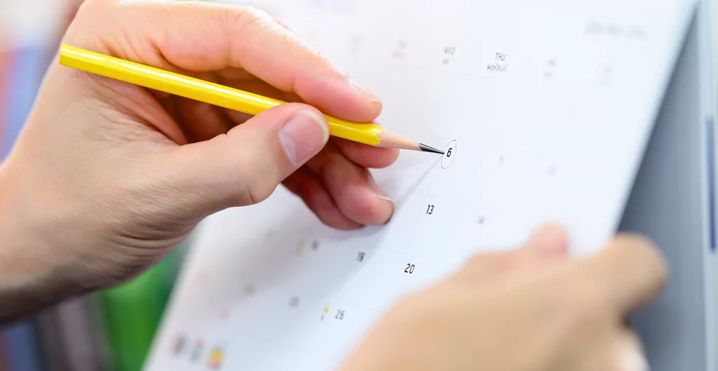 Mão segurando um lápis e um calendário