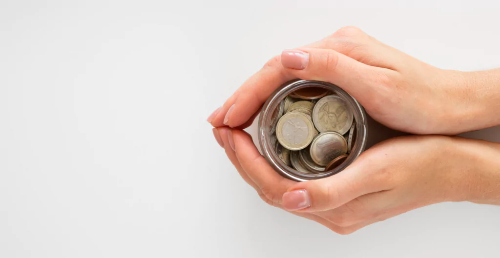 Mãos segurando um pote com moedas