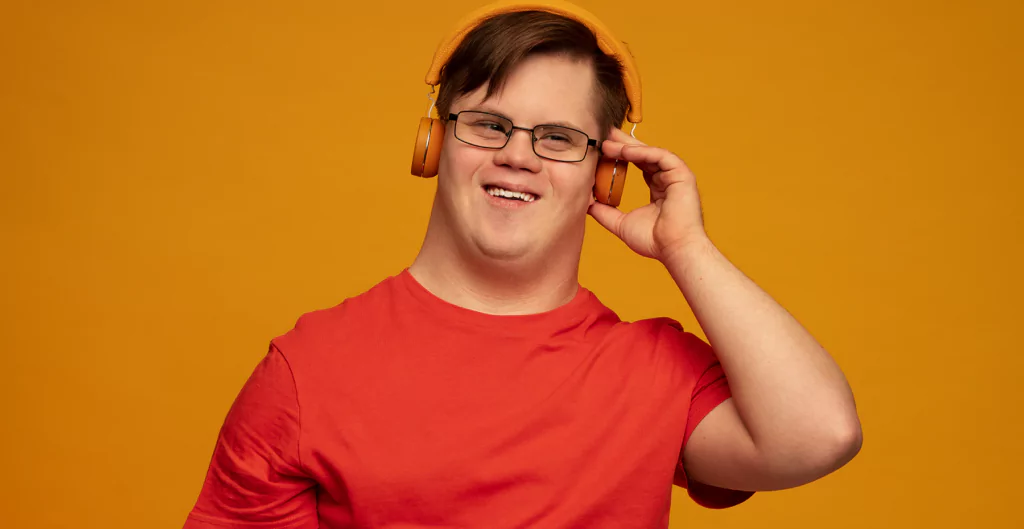 Um homem de óculos e camisa vermelha sorrindo com fones de ouvido
