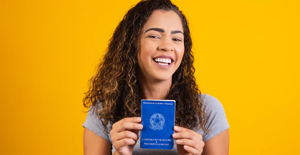 Uma mulher sorridente segurando uma carteira de trabalho