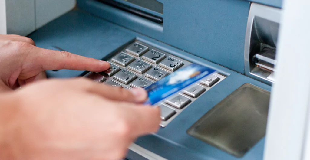 Uma pessoa está usando um cartão de crédito em um caixa eletrônico
