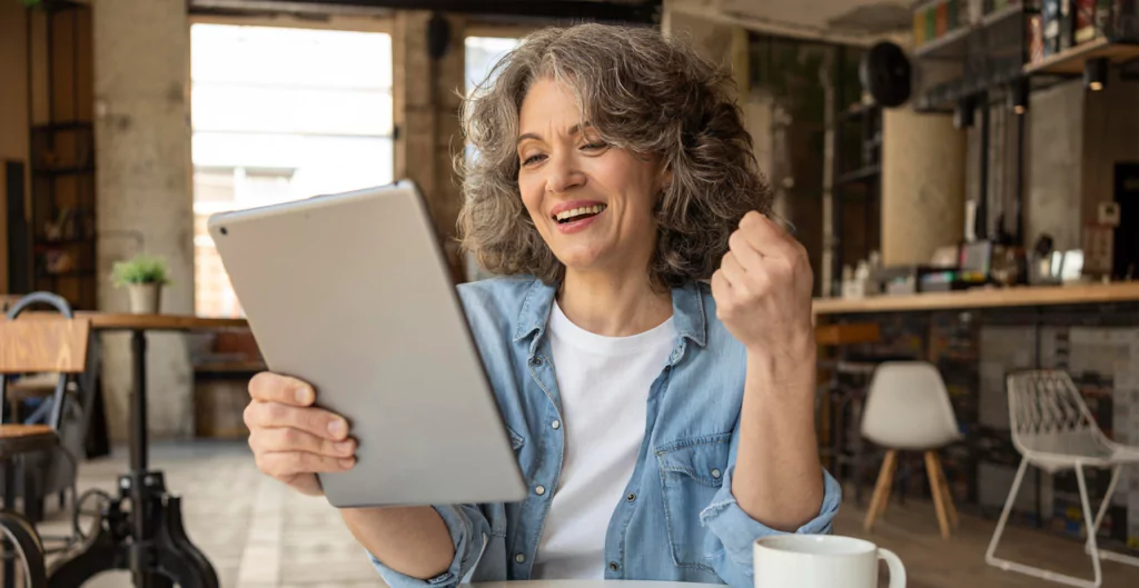 Imagem mostra uma mulher mexendo em um tablet com expressão de felicidade 