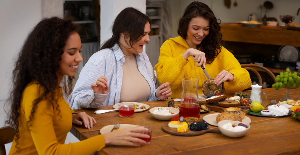 Três mulheres sentadas em uma mesa comendo comida