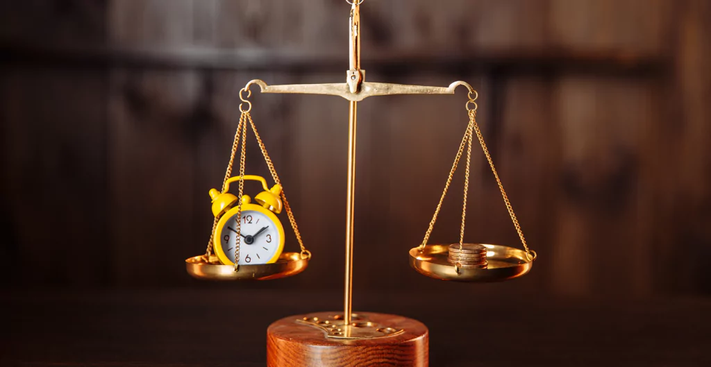 Um relógio e moedas em uma balança em cima de uma mesa de madeira