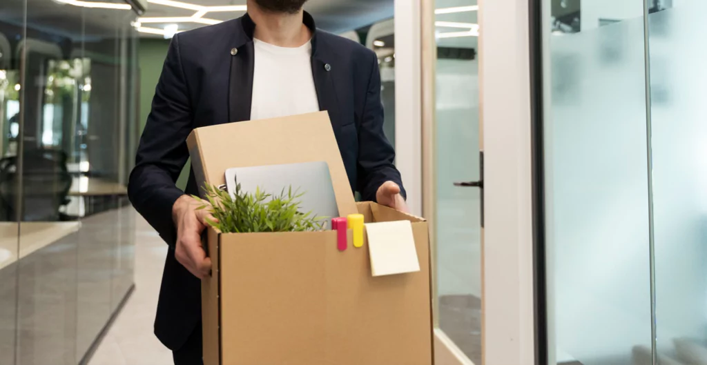 Um homem segurando uma caixa de papelão com uma planta nela e cpisas do trabalho