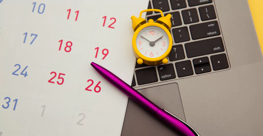 Um calendário, um relógio, uma caneta em um laptop