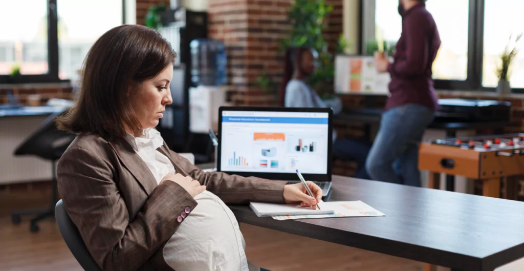 mulher grávida escrevendo e usando o computador
