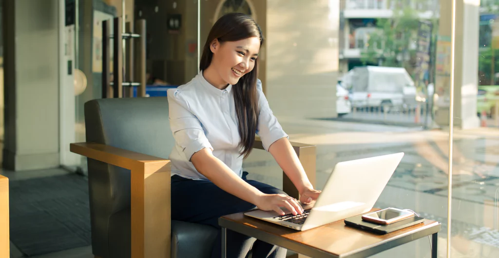 Uma mulher sentada à mesa com seu laptop