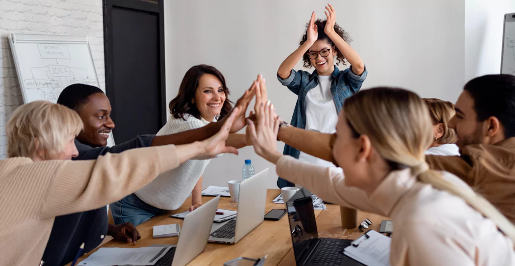 grupo de pessoas comemorando em uma sala de reunião 