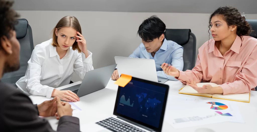 Um grupo de pessoas sentadas em torno de uma mesa com laptops