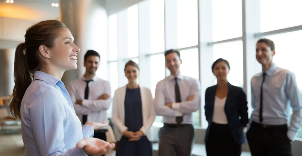 Uma mulher está de pé na frente de um grupo de empresários