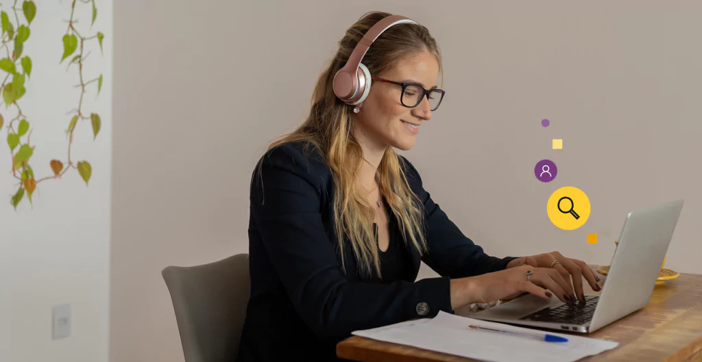 Mulher sorridente usando óculos e headphones, trabalhando em um laptop em um ambiente de escritório caseiro decorado com plantas