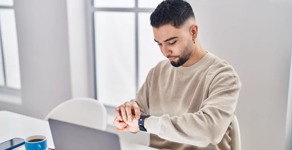 Homem em escritório moderno verificando o tempo em seu smartwatch