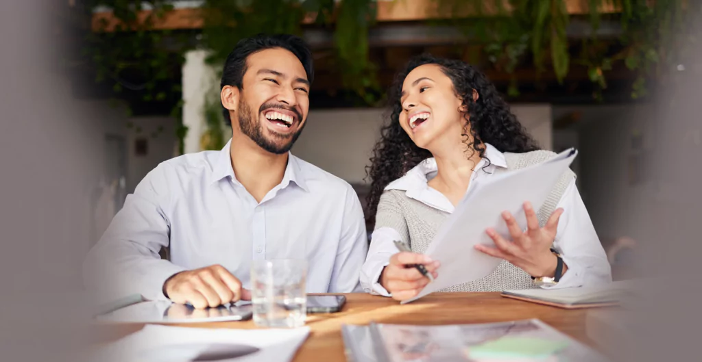 um homem e uma mulher sorridentes sentadas em uma mesa 