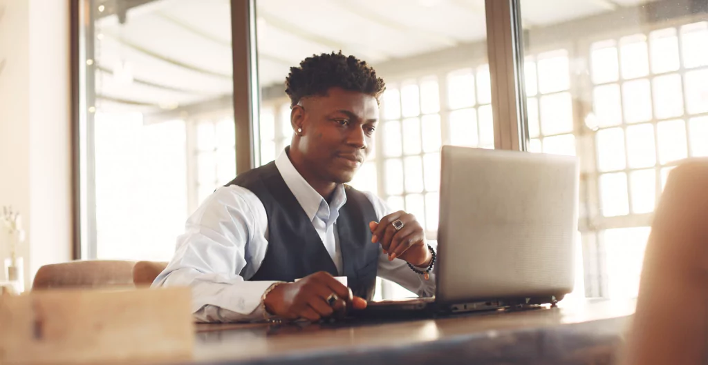 imagem de um homem sentado em uma mesa em um escritório e mexendo no notebook 