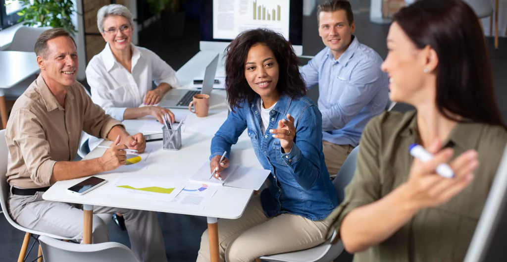 Equipe em reunião discutindo prioridades no trabalho, com gráficos e anotações.