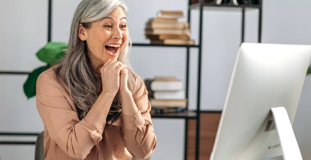 Mulher idosa asiática surpresa olhando para tela de um computador