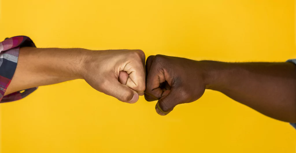 Toque de punhos entre duas pessoas, simbolizando camaradagem e respeito.