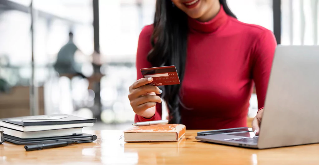 imagem mostra uma mulher mexendo no notebook e usando um cartão corporativo 