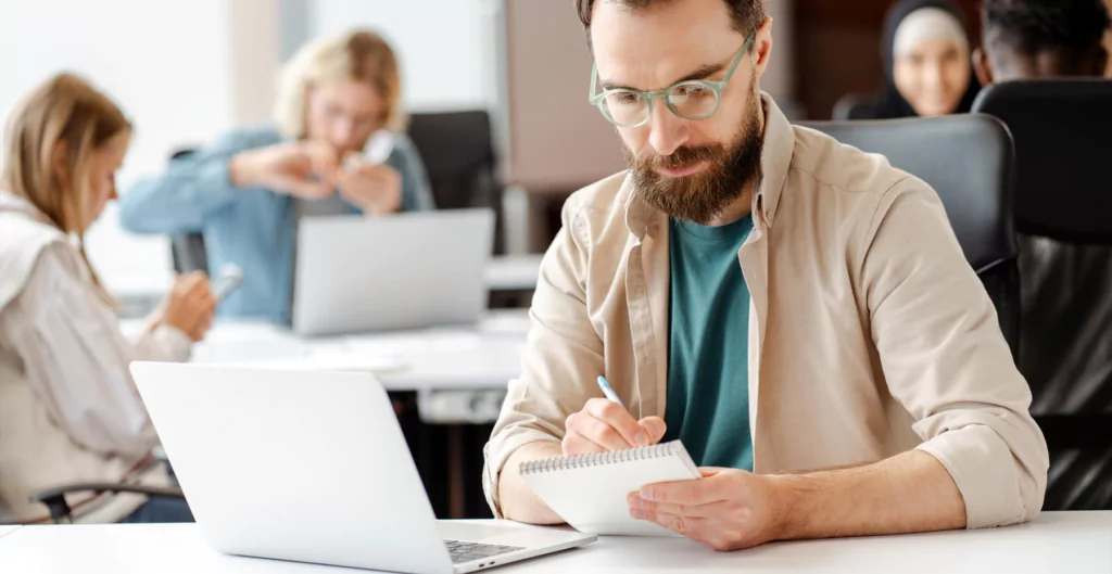 homem em um escritório fazendo anotações em uma caderneta 