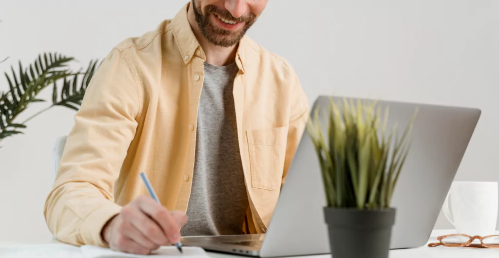 Homem anotando informações enquanto participa de entrevista online