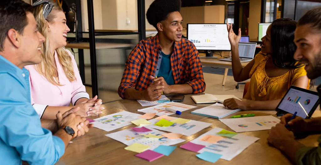 Equipe colaborando em ideias inovadoras com gráficos e post-its coloridos.