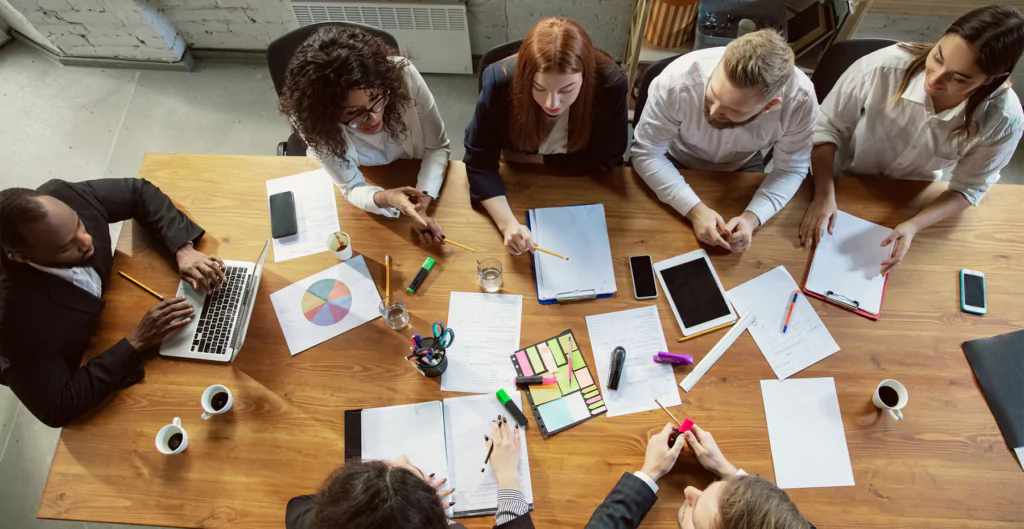 Vista aérea de reunião de equipe com documentos e dispositivos, planejando um sprint.