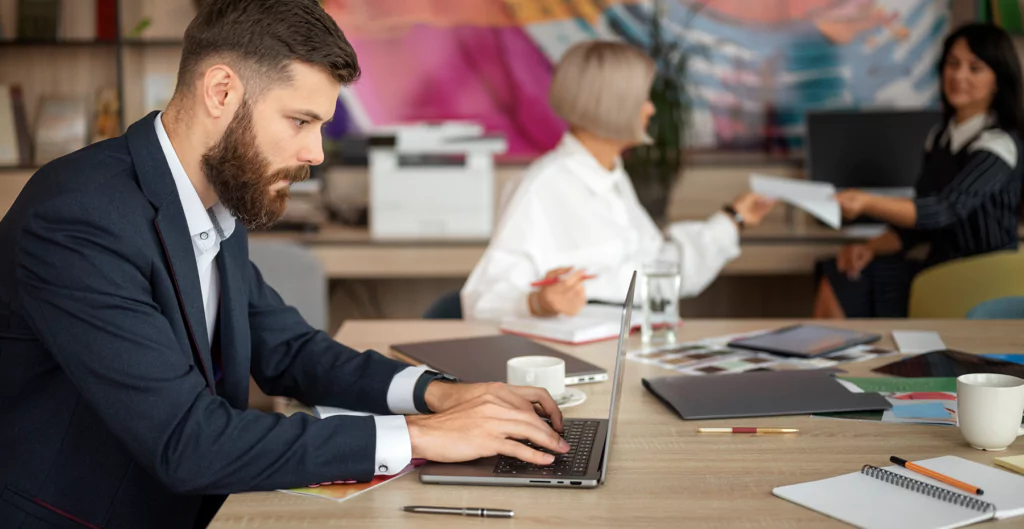 Homem em escritório digitando no laptop, simbolizando práticas de RH para eficiência no trabalho.