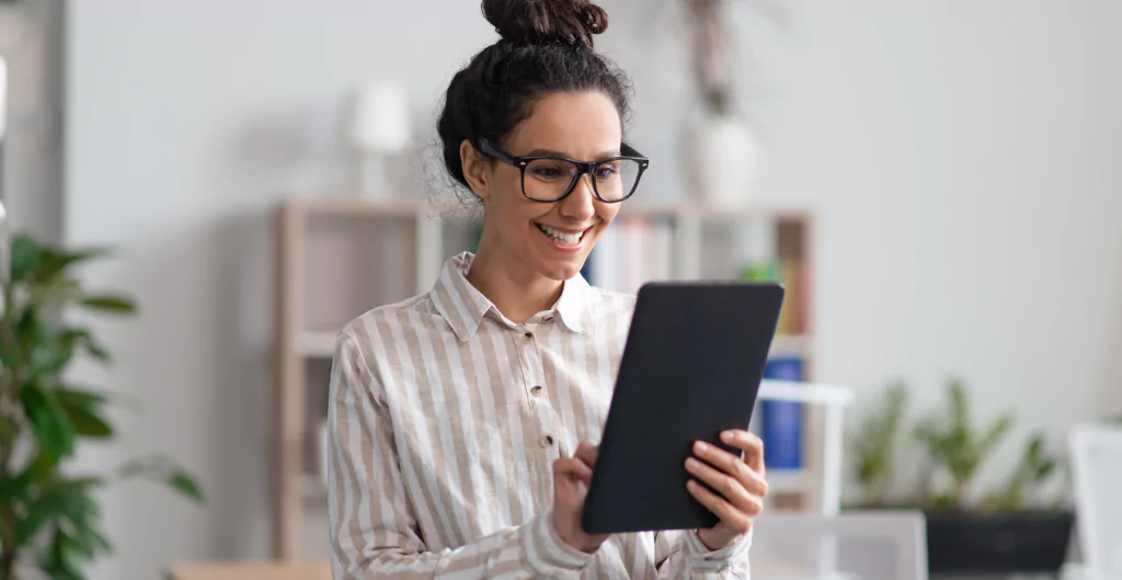 mulher sorridente olhando um tablet 