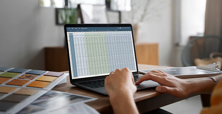 Notebook aberto, com uma planilha no excel, sobre uma mesa em um escritório simples