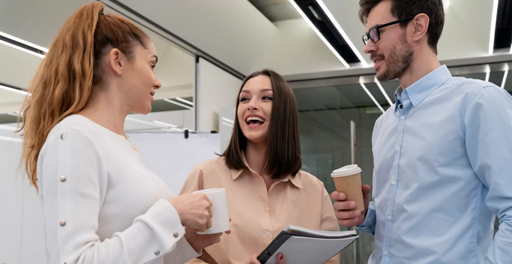 mulher sorrindo conversando com outra mulher e um homem, representando o marketing pessoal