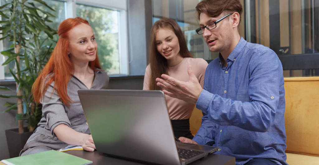 três pessoas sentadas mexendo no ponto digital no computador 