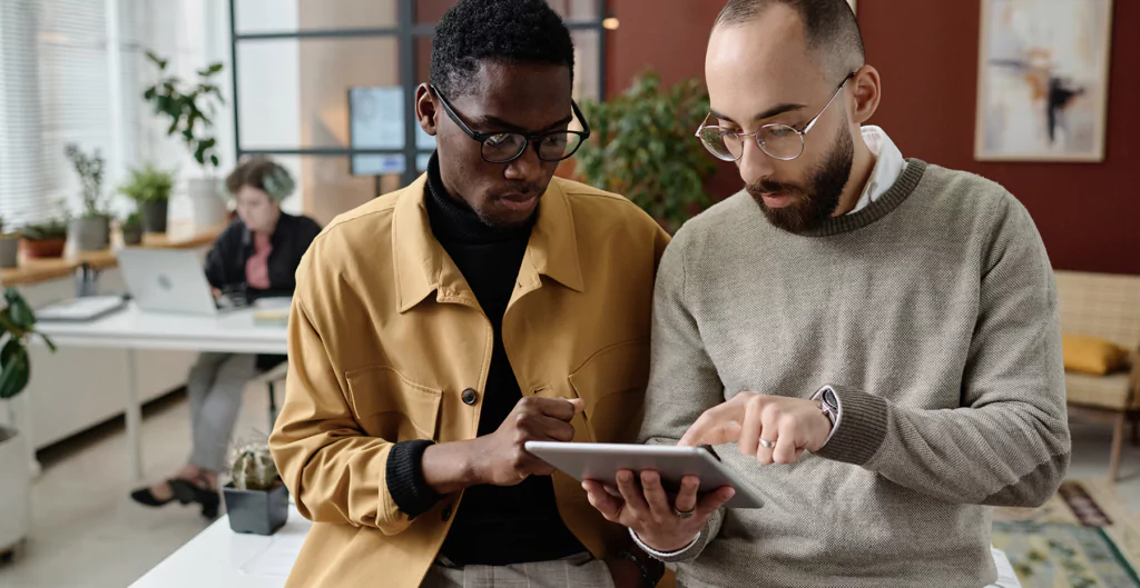 dois homens conversando e olhando para um tablet 