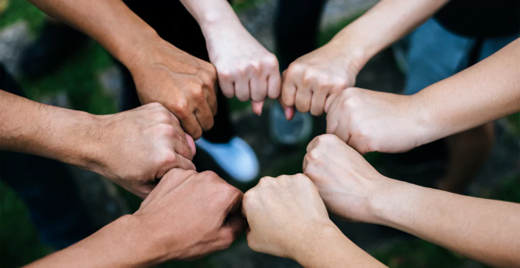 Pessoas unindo os punhos em um gesto de colaboração comunitária.