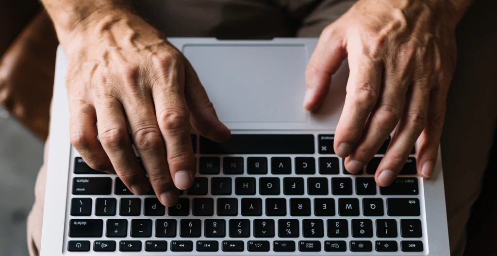 Mãos digitando em laptop, simbolizando busca e análise em processos sigilosos.