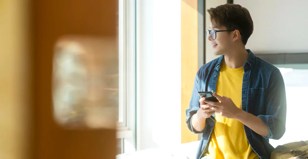 Jovem aprendiz olhando o celular com expressão motivada, representando flexibilidade no controle de ponto.