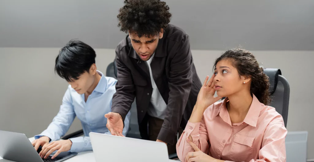 três pessoas discordando sentados em uma mesa de escritório