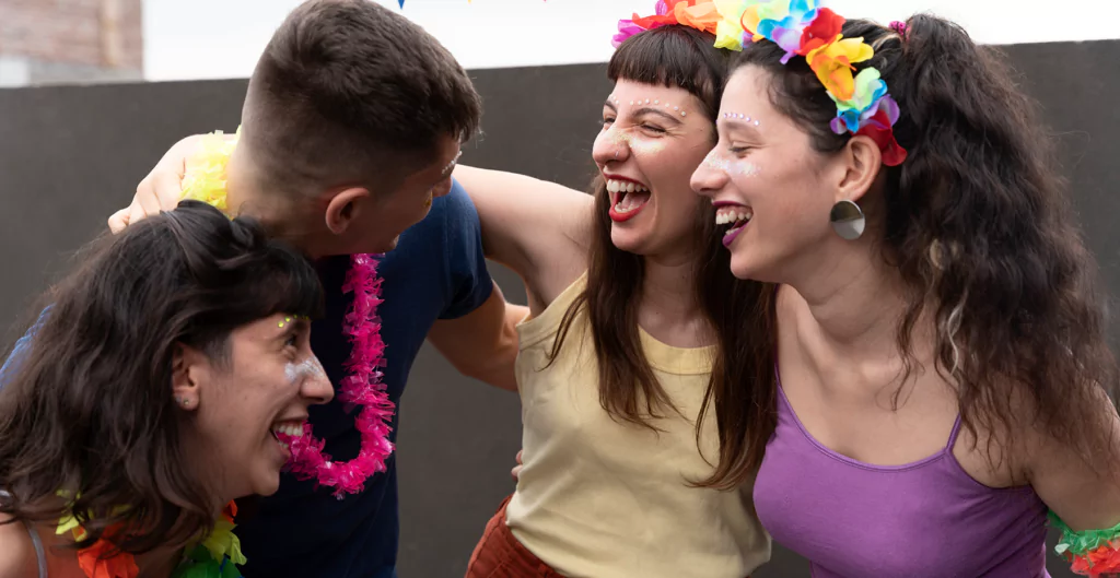 Quatro pessoas com roupas e maquiagens de carnaval sorrindo 