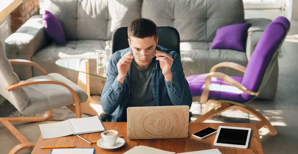 homem sentado de frete para o notebook com expressão de assustado 