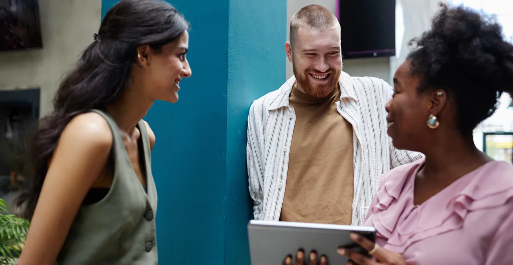 imagem de um homem e duas mulheres conversando num ambiente corporativo, representando a inteligência comportamental