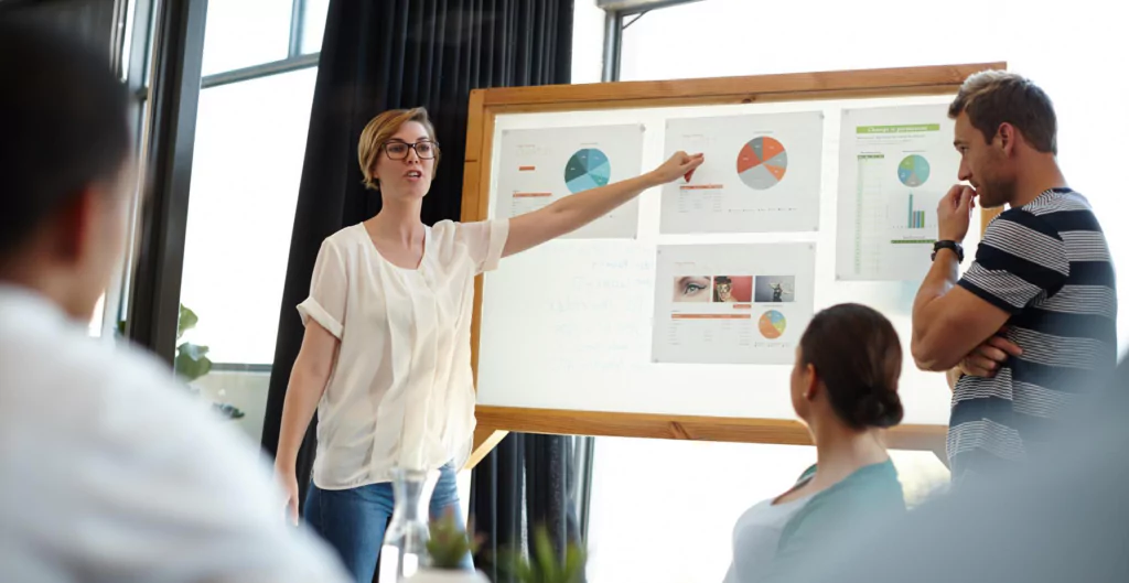 Mulher apresentando um quadro com informações e planejamento para equipe 