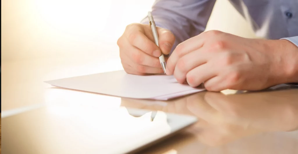 homem assinando um papel, representando a rescisão de contrato em caso de falência