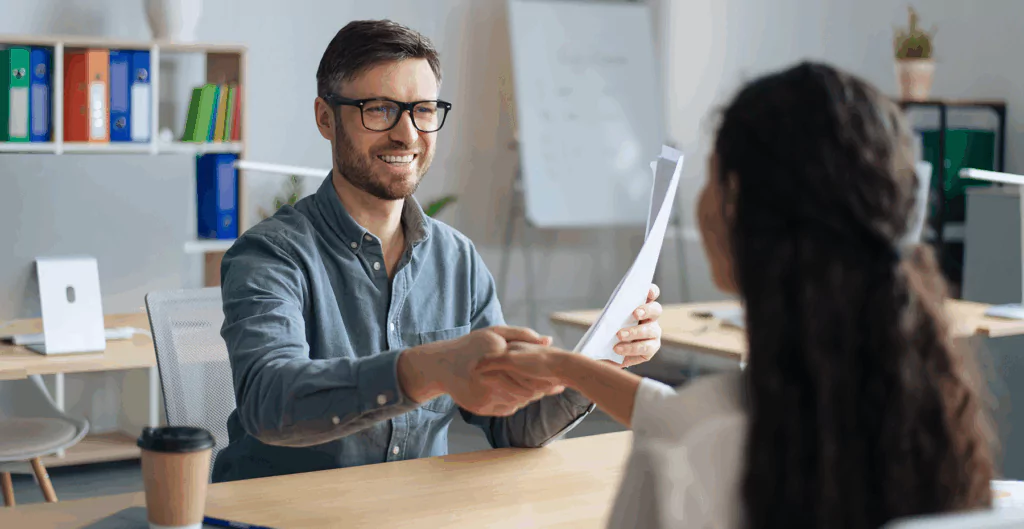 Homem entregando uma proposta ou documento para uma mulher em um ambiente de escritório, símbolo de sucesso profissional e negociações bem-sucedidas.