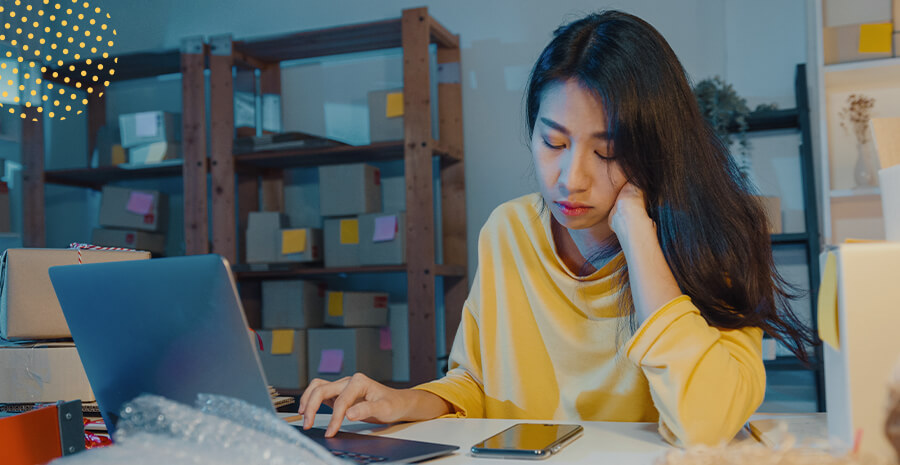 imagem de uma mulher em frente a um computador cabisbaixa 
