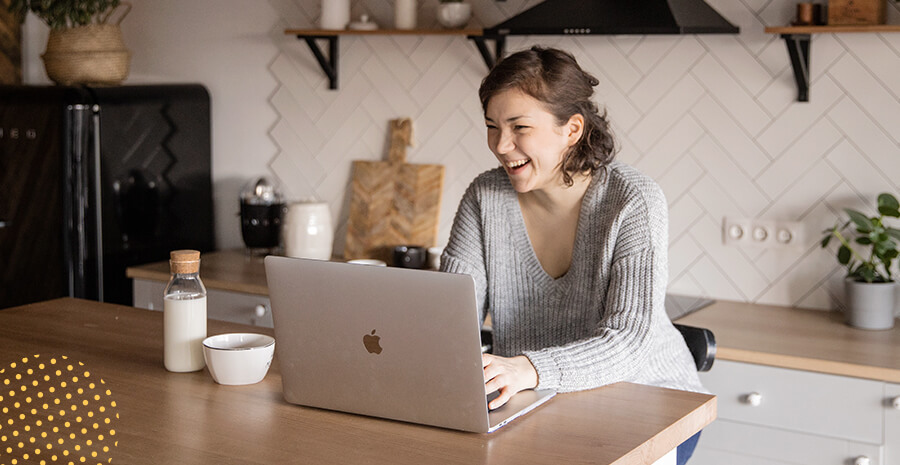 imagem de uma mulher olhando para o computador, ela ri